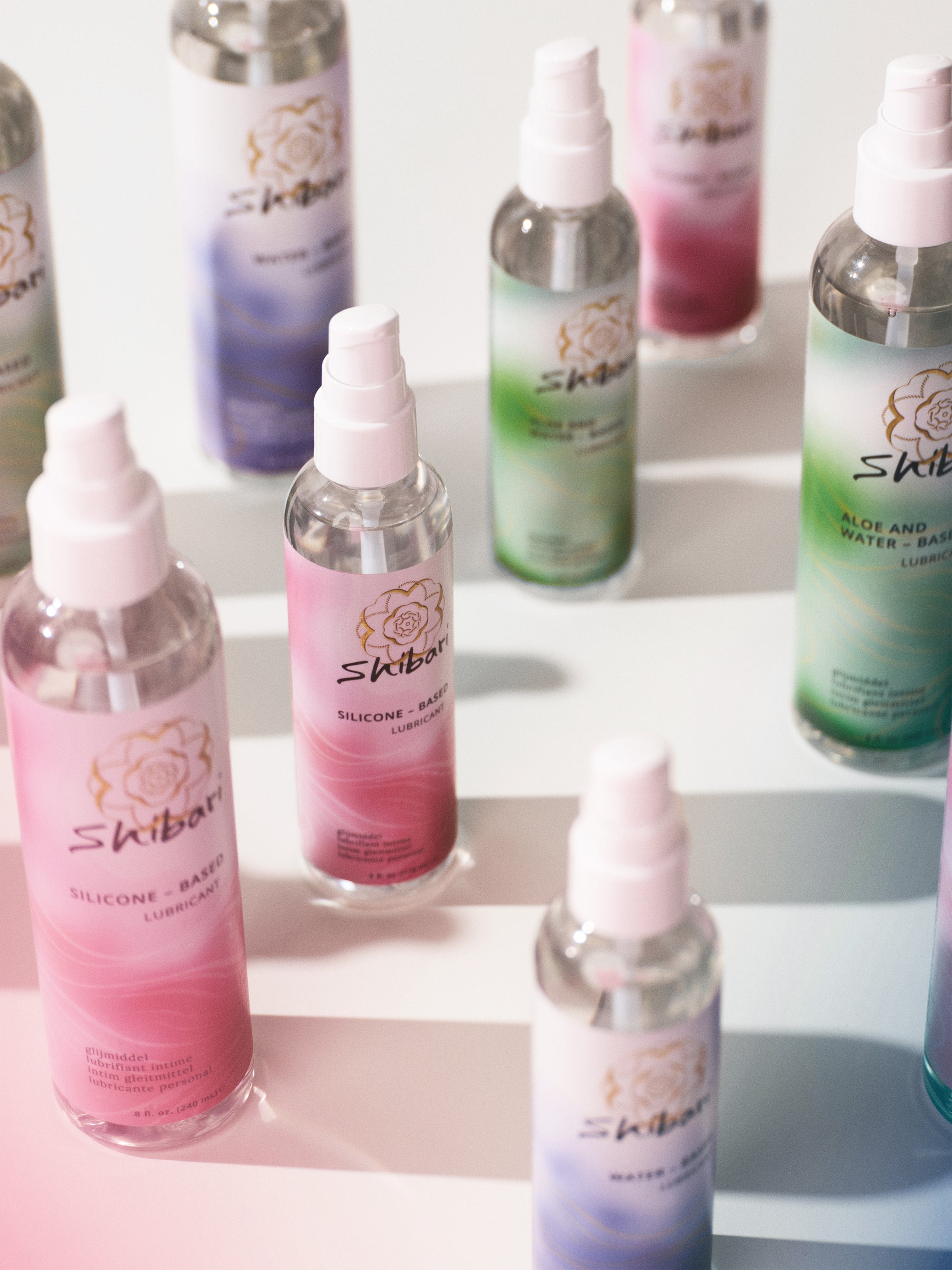Bottles of Shibari lubricants on a white surface with gradient background